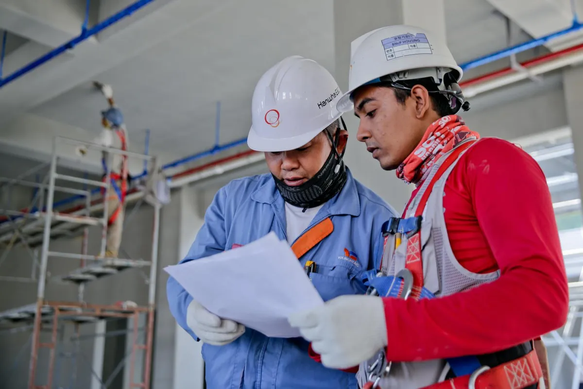 Construction workers wearing PPE including hard hats and high-visibility vests on UK building site