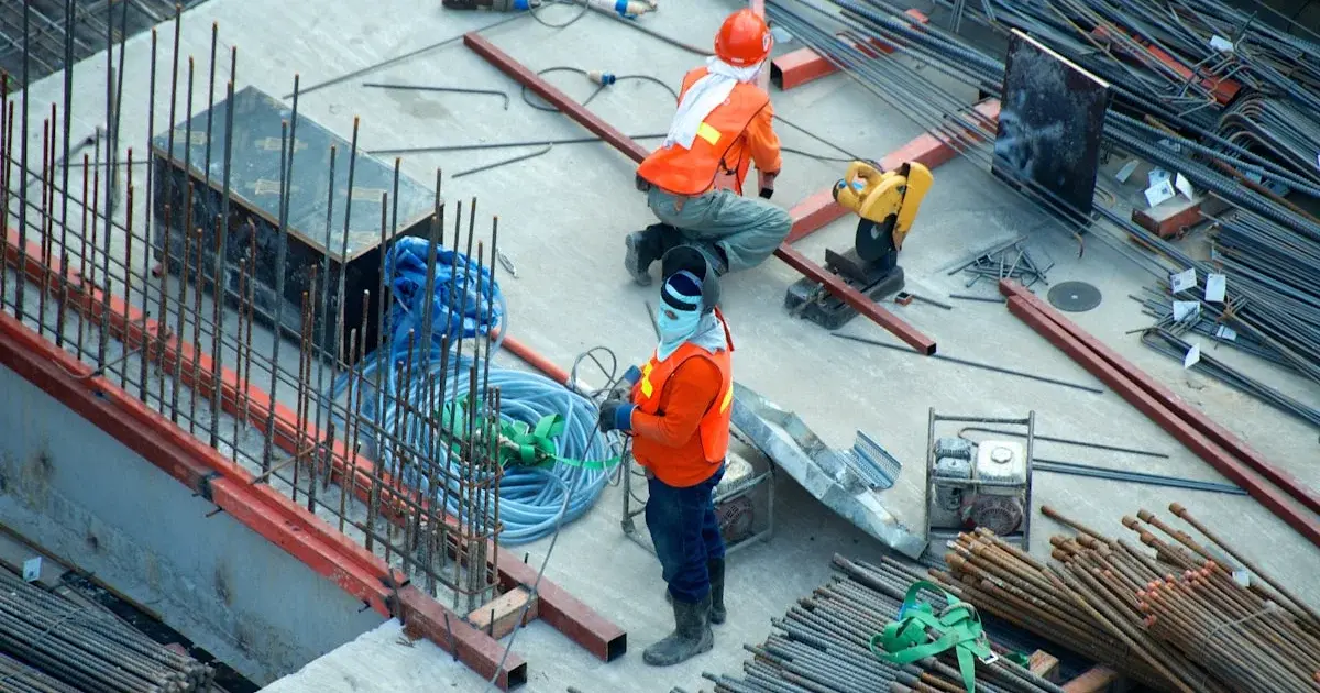 Site manager using tablet on construction site with workers in background
